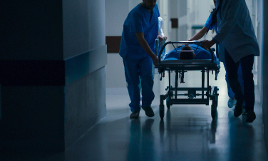 two orderlies pushing a patient on a stretcher down a hospital hallway