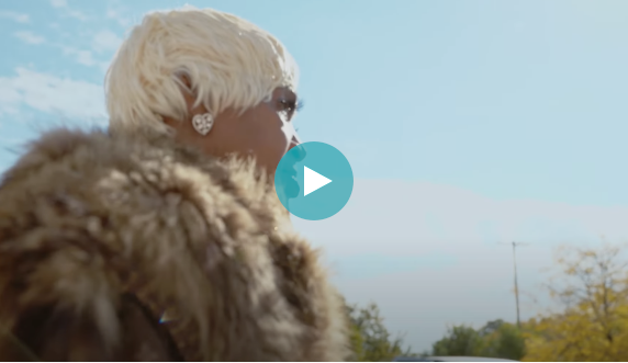 Photo of person with blond hair and fur coat looking off into distance  - click to view video